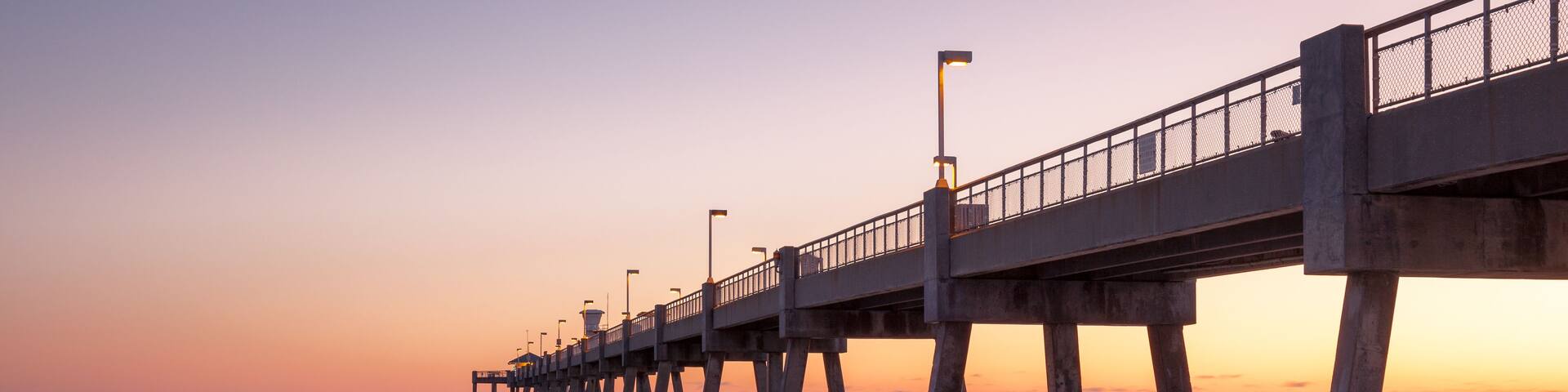 A pier extending into calm waters at sunset.