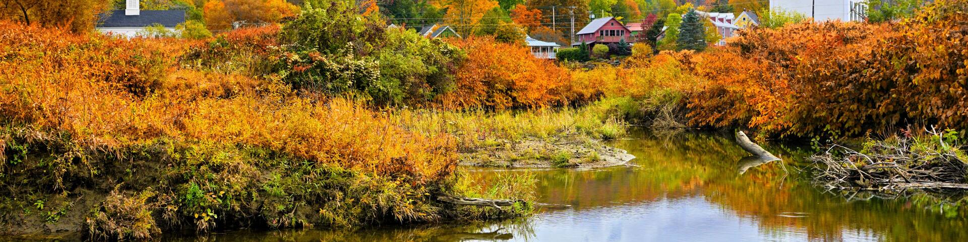 Autumn view of the town of Stowe with white church and fall colors along the Little River, Vermont, USA