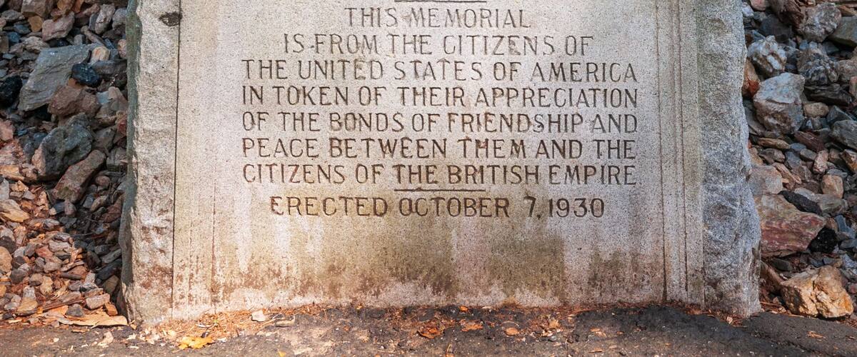 A memorial stone with inscriptions and a coat of arms, surrounded by a forest.