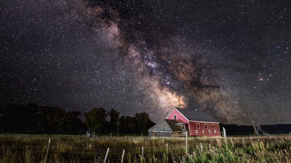 A red barn under a starry night sky with the Milky Way visible.