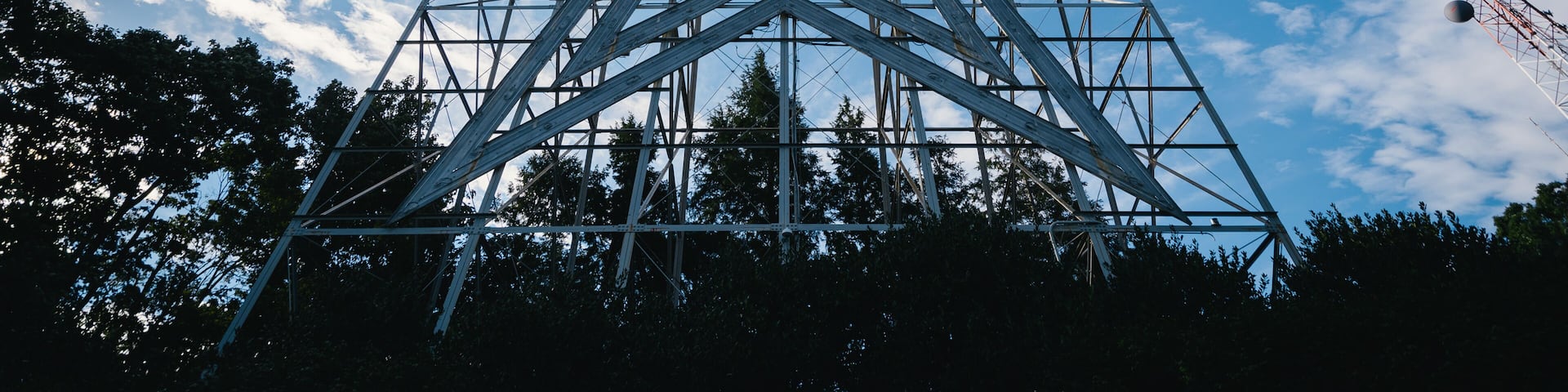 A large metal framework structure against a partly cloudy sky.