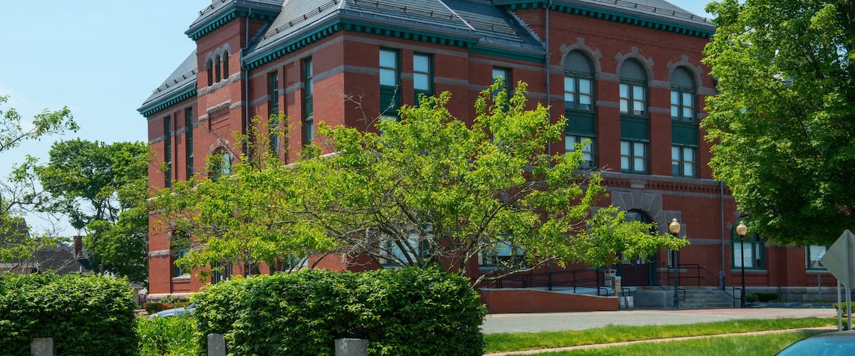 A large red brick building with a green roof and arched windows.