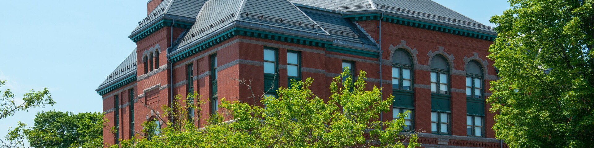 A large red brick building with a green roof and arched windows.