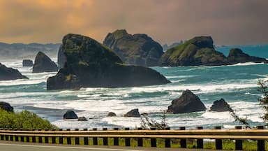 A coastal road with a truck, surrounded by rugged cliffs and waves.