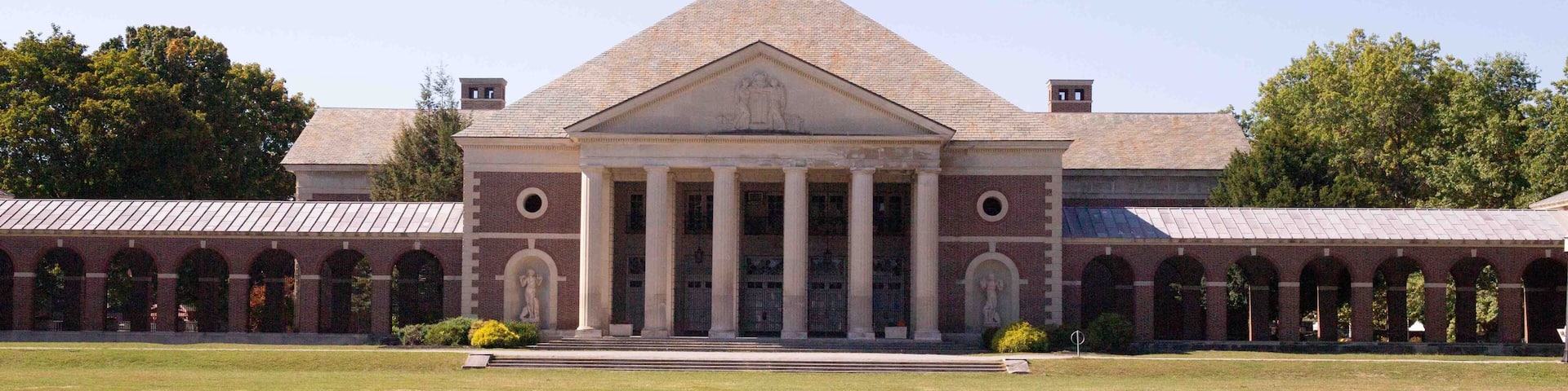 A large building with a central portico and a symmetrical facade, surrounded by a reflective water feature.