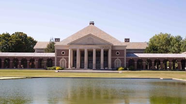 A large building with a central portico and a symmetrical facade, surrounded by a reflective water feature.
