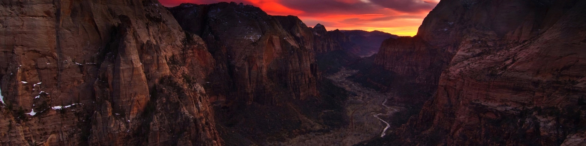 A canyon with layered rock formations and a winding road at the bottom.