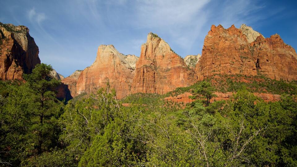 A mountainous landscape with prominent red rock formations and dense green foliage.