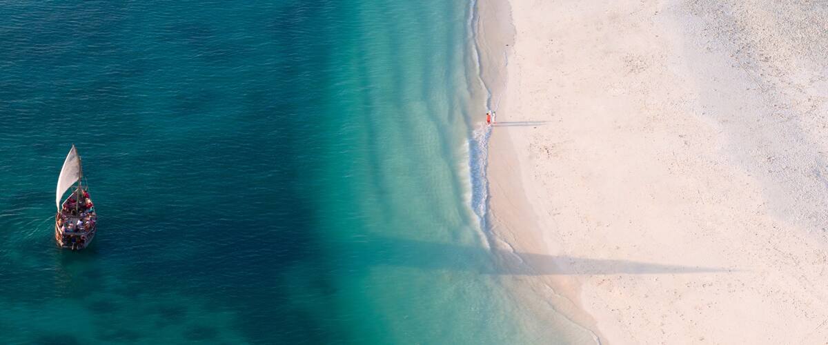 A boat on turquoise waters near a sandy beach.
