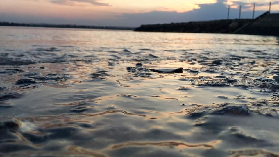 A body of water with ripples and a sunset in the background.