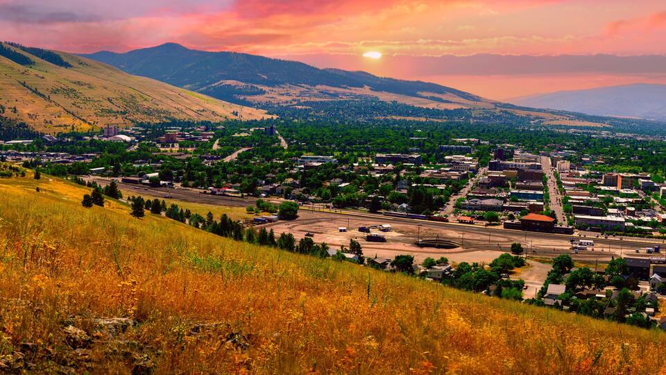 A town nestled in a valley with mountains in the background.