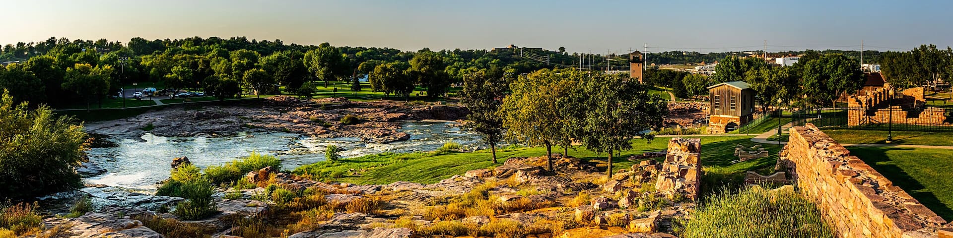 A river flowing through a rocky landscape with trees and ancient ruins.