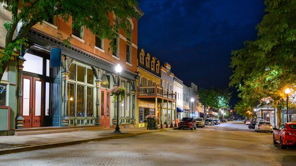 Early American buildings with shops and boutiques line the brick paved Main Street in the historic small town of St. Charles Missouri at night.