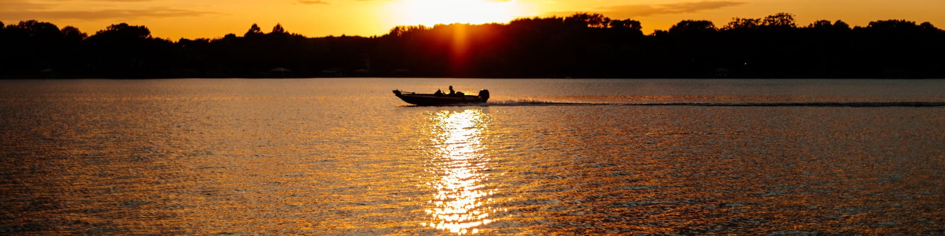 Beautiful sky and lake with boats, people relaxing on the shore at sunset. Beautiful orange and blue sky at dawn. Lake Bowen Anchor Park, Inman, SC, USA