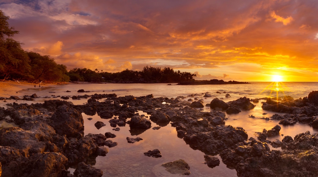 A rocky shoreline with a sunset over the ocean.