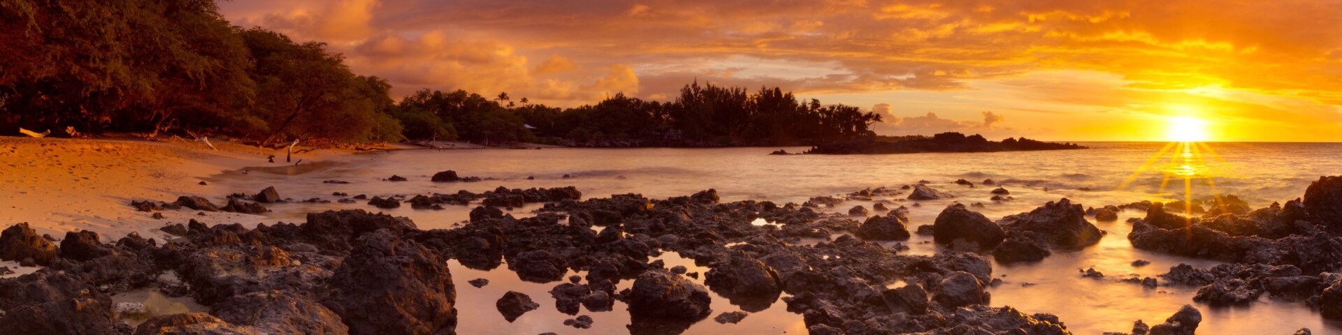 Une côte rocheuse avec un coucher de soleil sur l’océan.