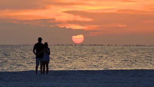 Beach lovers watch the sunset over Sanibel Island from Fort Myers Beach, Florida, USA.