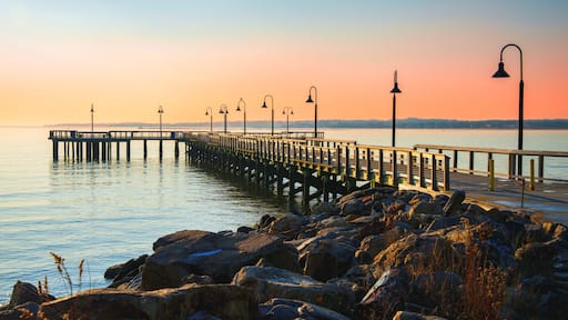 New England Seascape over Fishing Pier Boardwalk in New Haven Harbor in Connecticut at Sunrise: A tranquil beach walk spot with curving street light lamps and safety railing