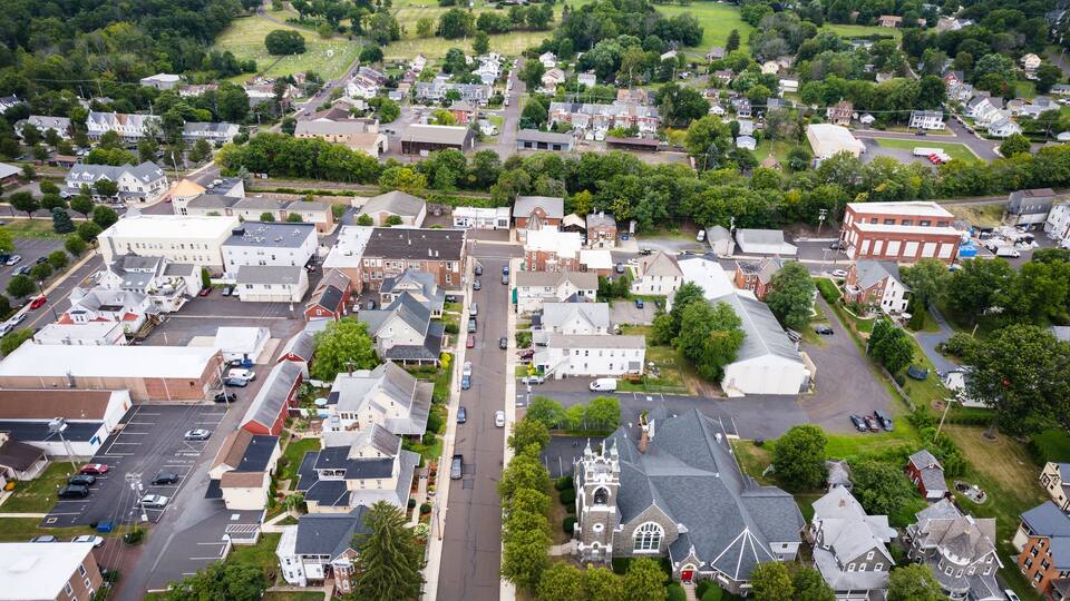 An aerial view of a small town with a mix of residential houses, a church, and a few commercial buildings.
