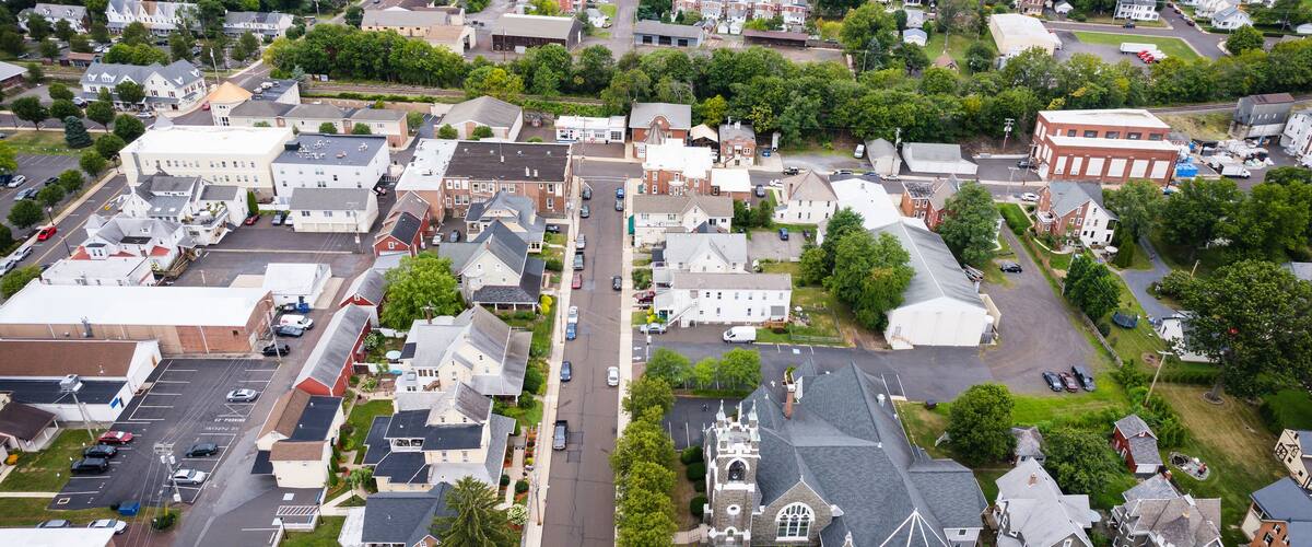 An aerial view of a small town with a mix of residential houses, a church, and a few commercial buildings.