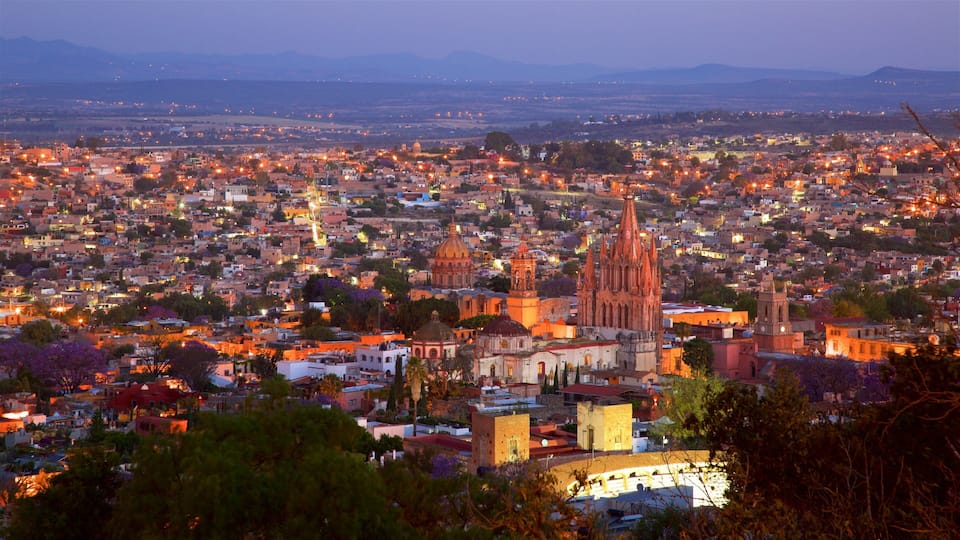A cityscape at dusk with prominent cathedral spires and domed buildings.