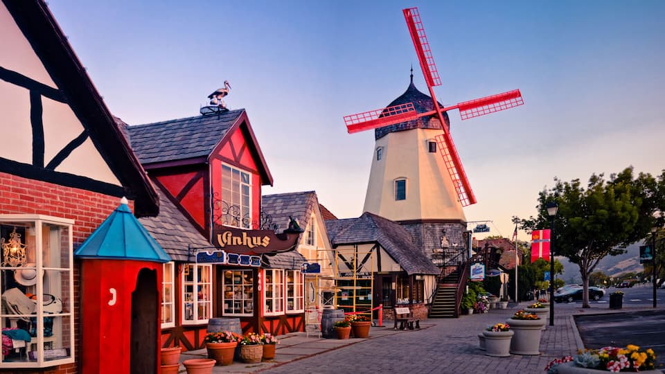 A traditional windmill, a red and white building, and a shop with a sign that reads "Vinhus".