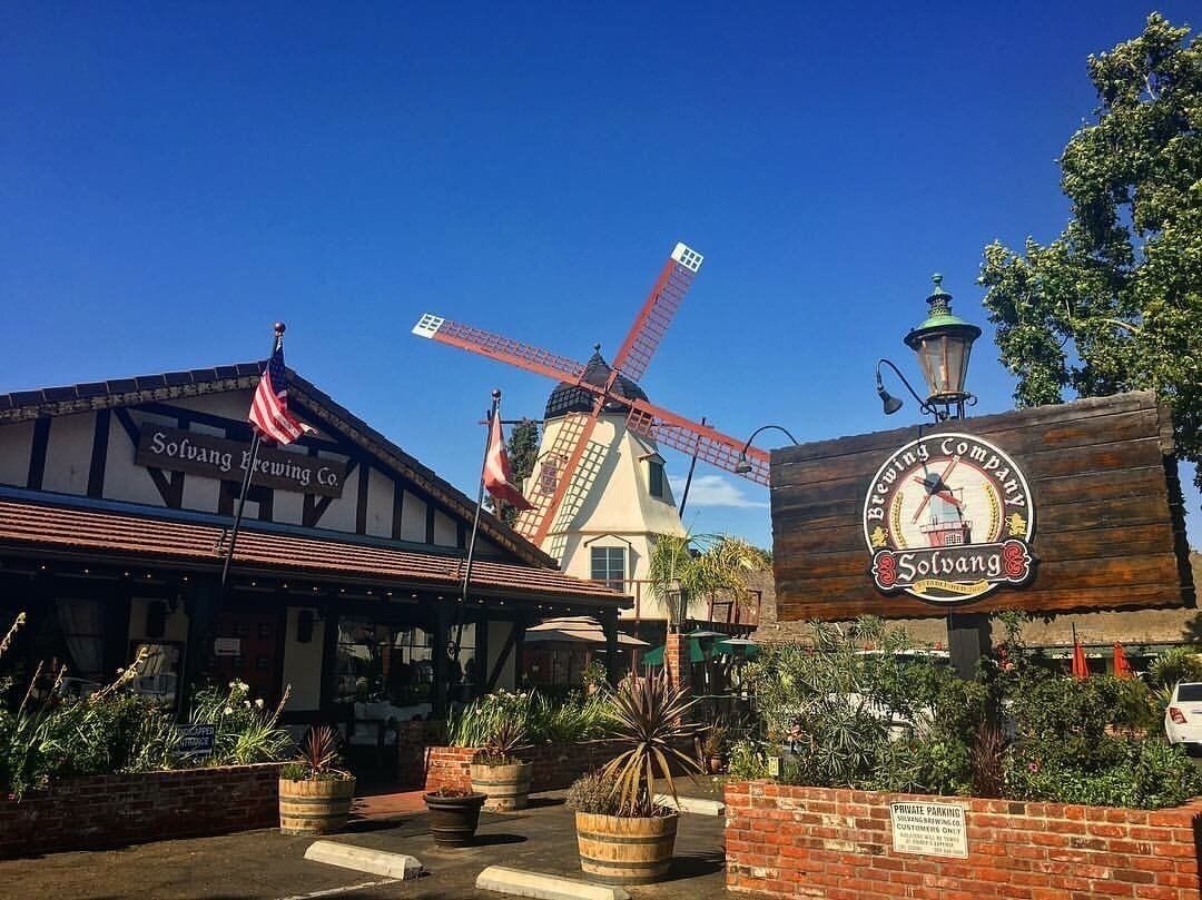A traditional windmill, a building labeled 'Solvang Brewing Co.', and a wooden sign with 'Solvang Brewing Company' and 'Solvang' text.