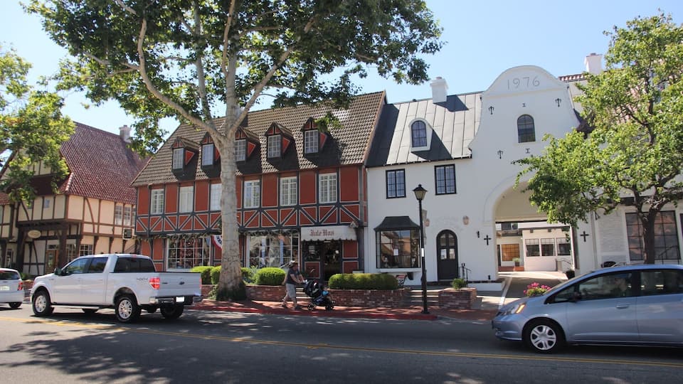 A street with historic buildings, a white pickup truck, and a silver car.