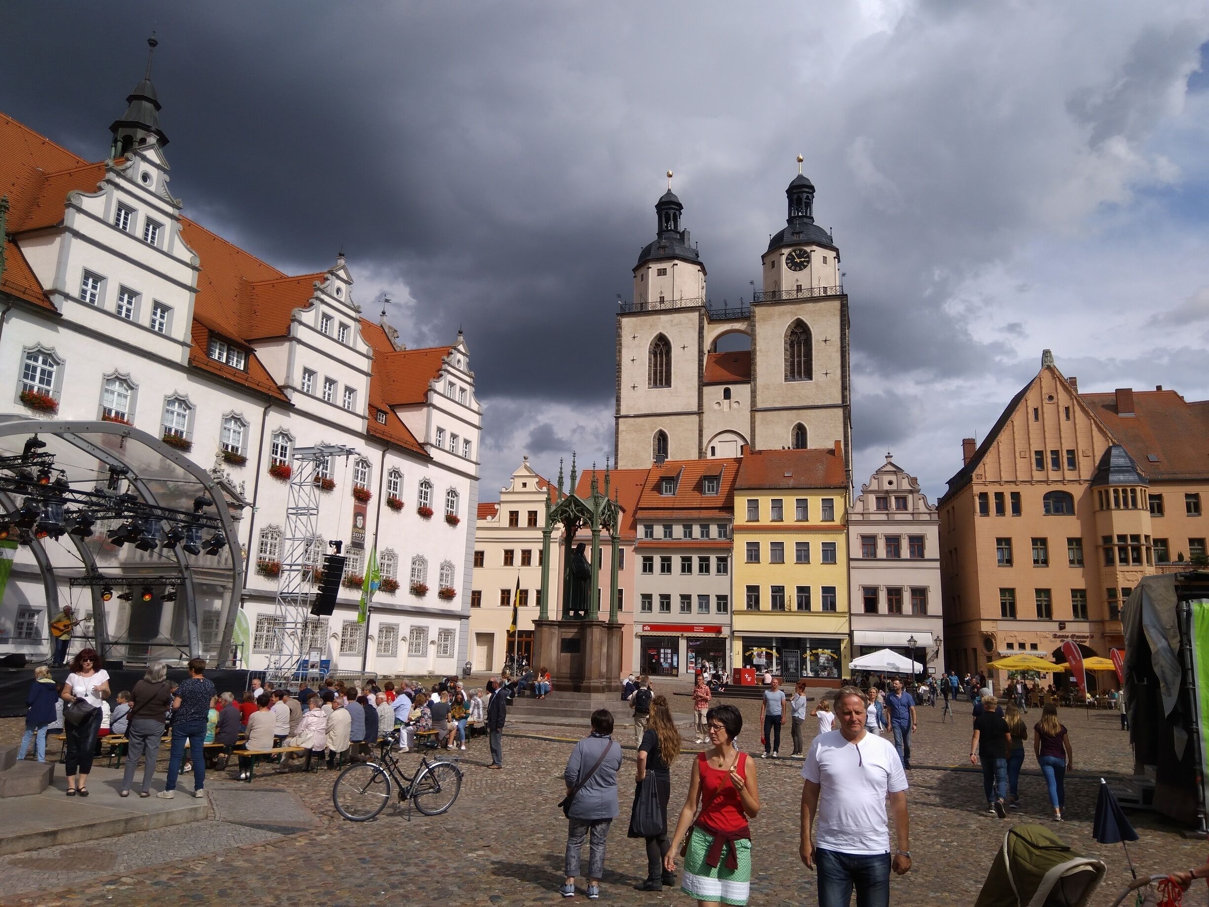 A historic square with a prominent church tower, cobblestone streets, and traditional European architecture.