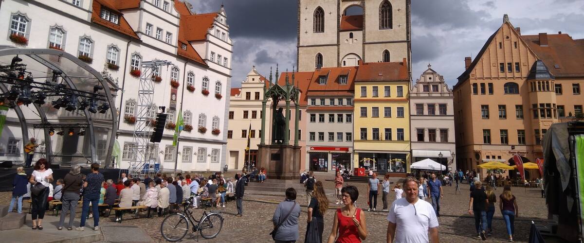 A historic square with a prominent church tower, cobblestone streets, and traditional European architecture.