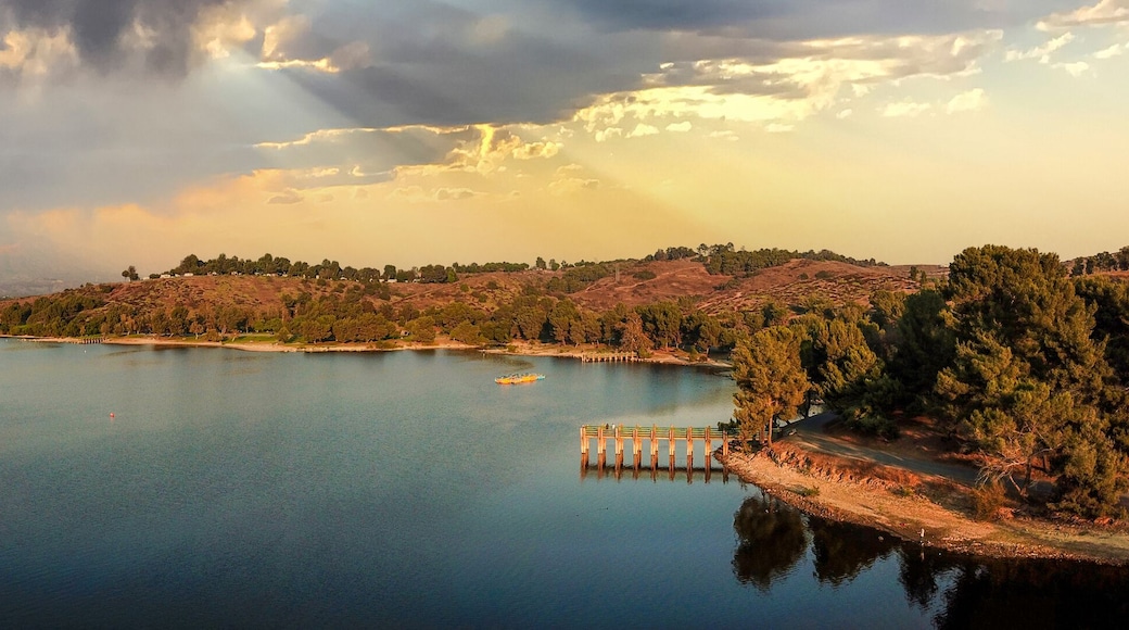 a breathtaking aerial panoramic shot of the still blue waters and lush green trees and majestic mountain ranges at Frank G Bonelli Regional Park at Puddingstone Lake in San Dimas California