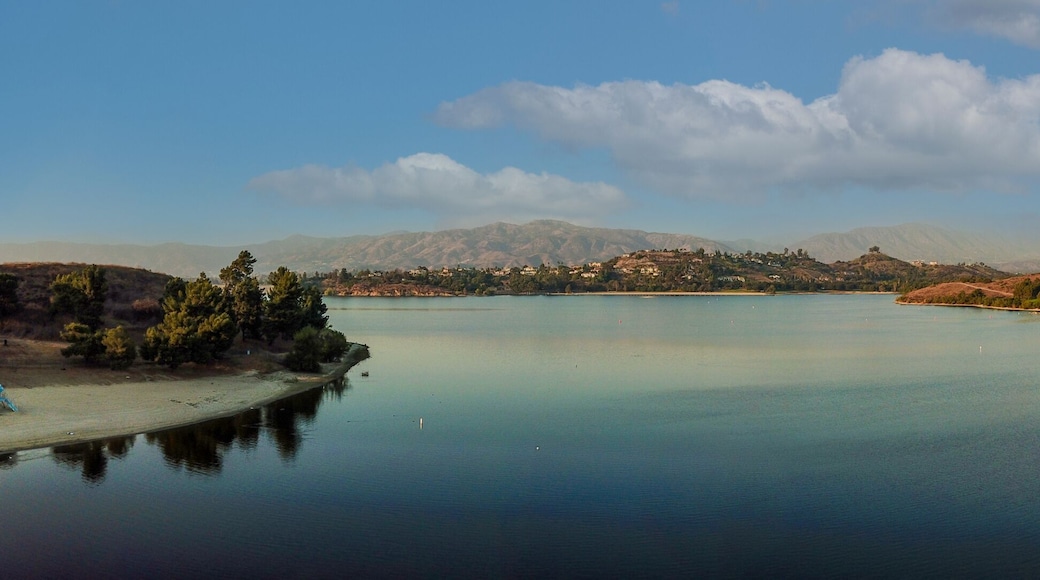 a breathtaking aerial panoramic shot of the still blue waters and lush green trees and majestic mountain ranges at Frank G Bonelli Regional Park at Puddingstone Lake in San Dimas California