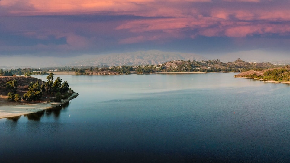 A calm lake surrounded by hills and trees.