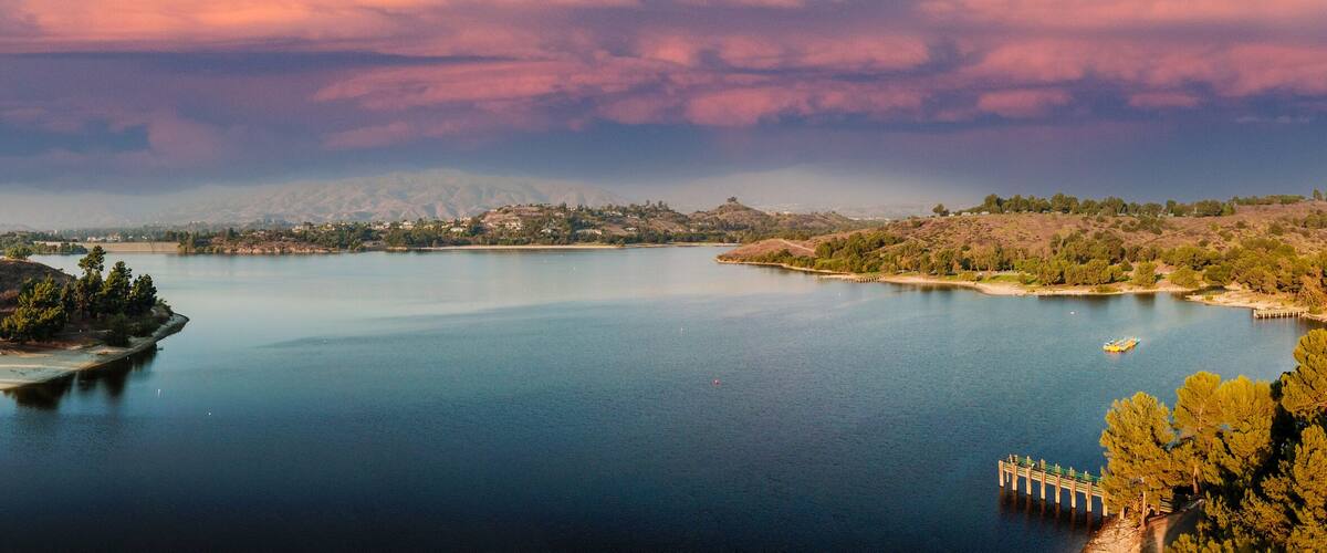 A calm lake surrounded by hills and trees.