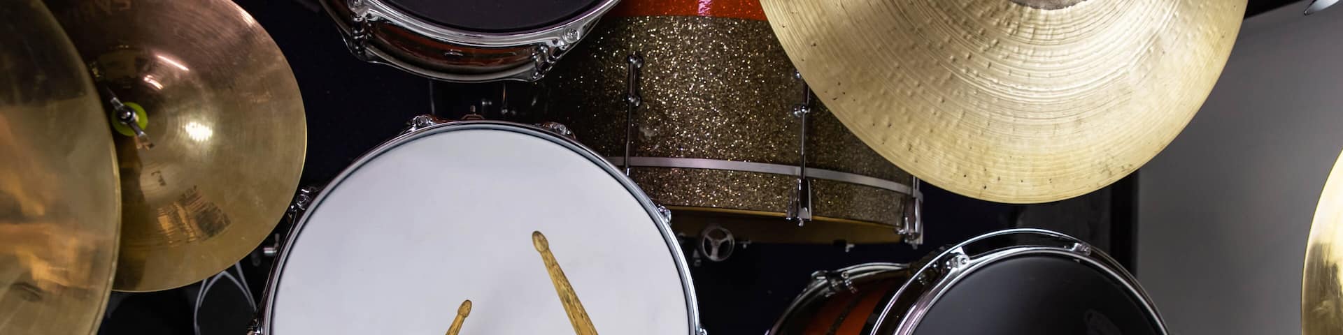 Musical instruments close up banner. Beautiful snare drum and hi-hat cymbals with drummer holding drumsticks. Modern drum set. Music shop.
