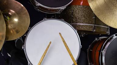 Musical instruments close up banner. Beautiful snare drum and hi-hat cymbals with drummer holding drumsticks. Modern drum set. Music shop.