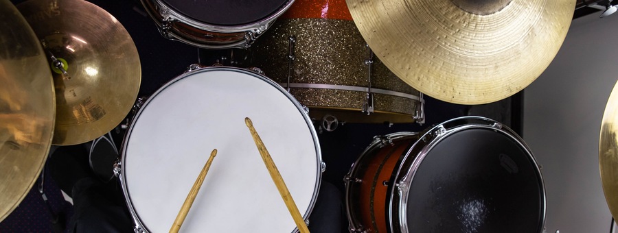 Musical instruments close up banner. Beautiful snare drum and hi-hat cymbals with drummer holding drumsticks. Modern drum set. Music shop.