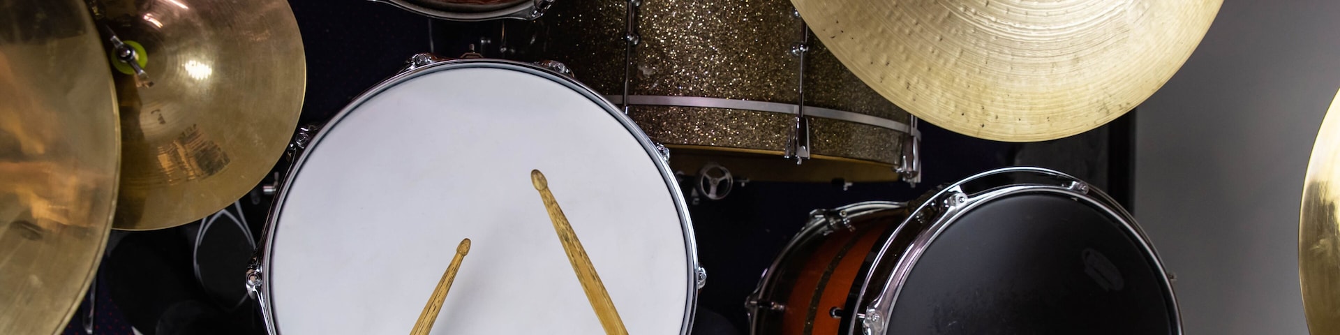 Musical instruments close up banner. Beautiful snare drum and hi-hat cymbals with drummer holding drumsticks. Modern drum set. Music shop.