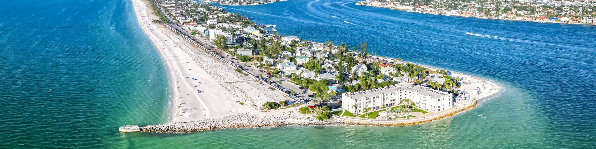 A coastal cityscape with a prominent beach, a marina, and a large building complex.