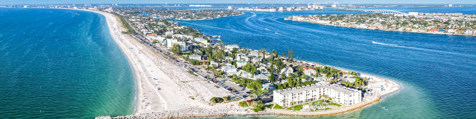 A coastal cityscape with a prominent beach, a marina, and a large building complex.