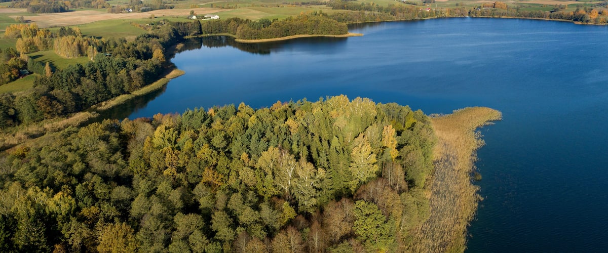 A large lake surrounded by dense forests and open fields.
