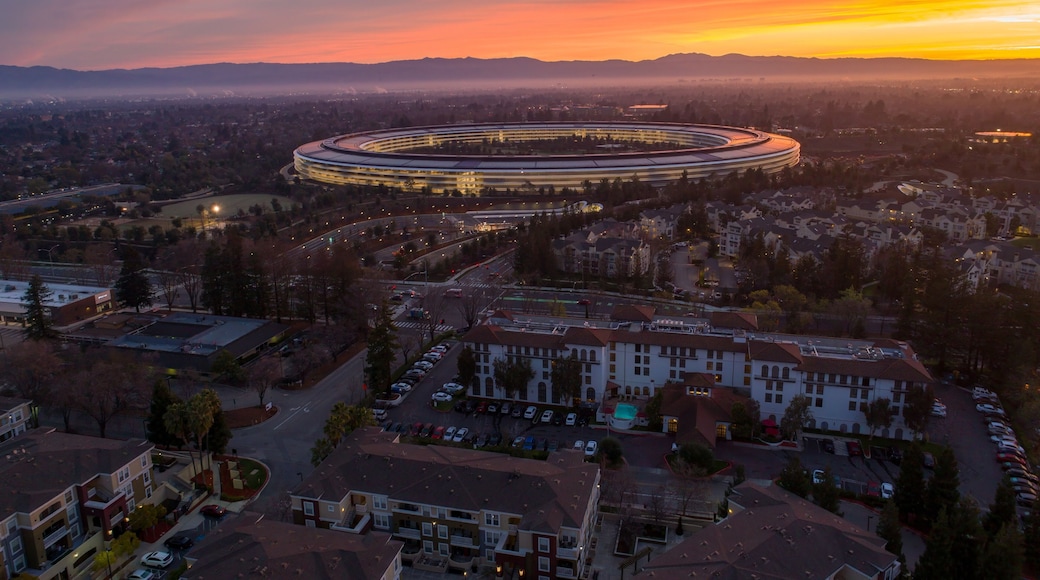 Aerial view of Apple Park at sunrise in Cupertino, California, USA. The corporate headquarters is lit up as employees arrive for work.