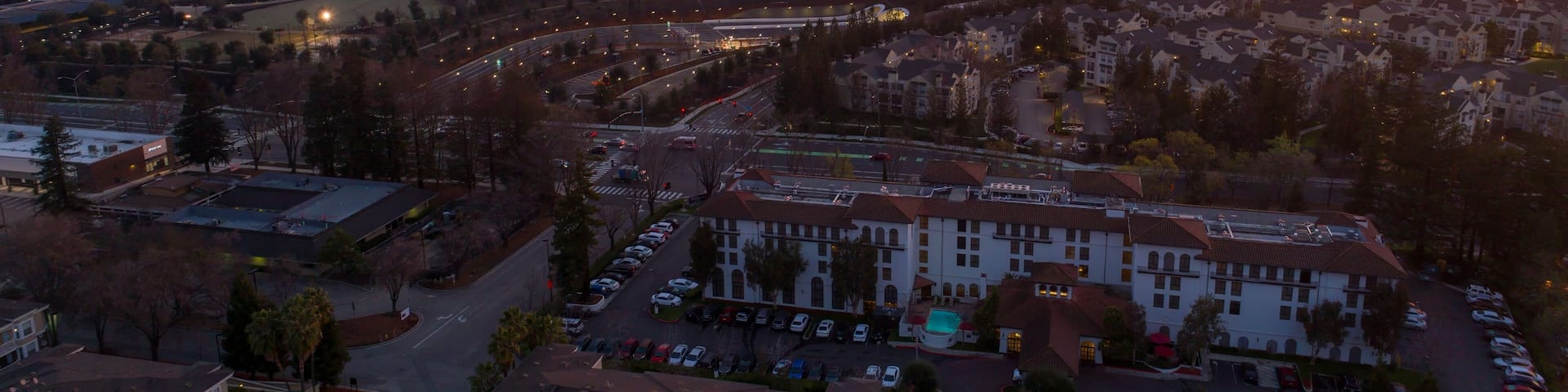 Aerial view of Apple Park at sunrise in Cupertino, California, USA. The corporate headquarters is lit up as employees arrive for work.
