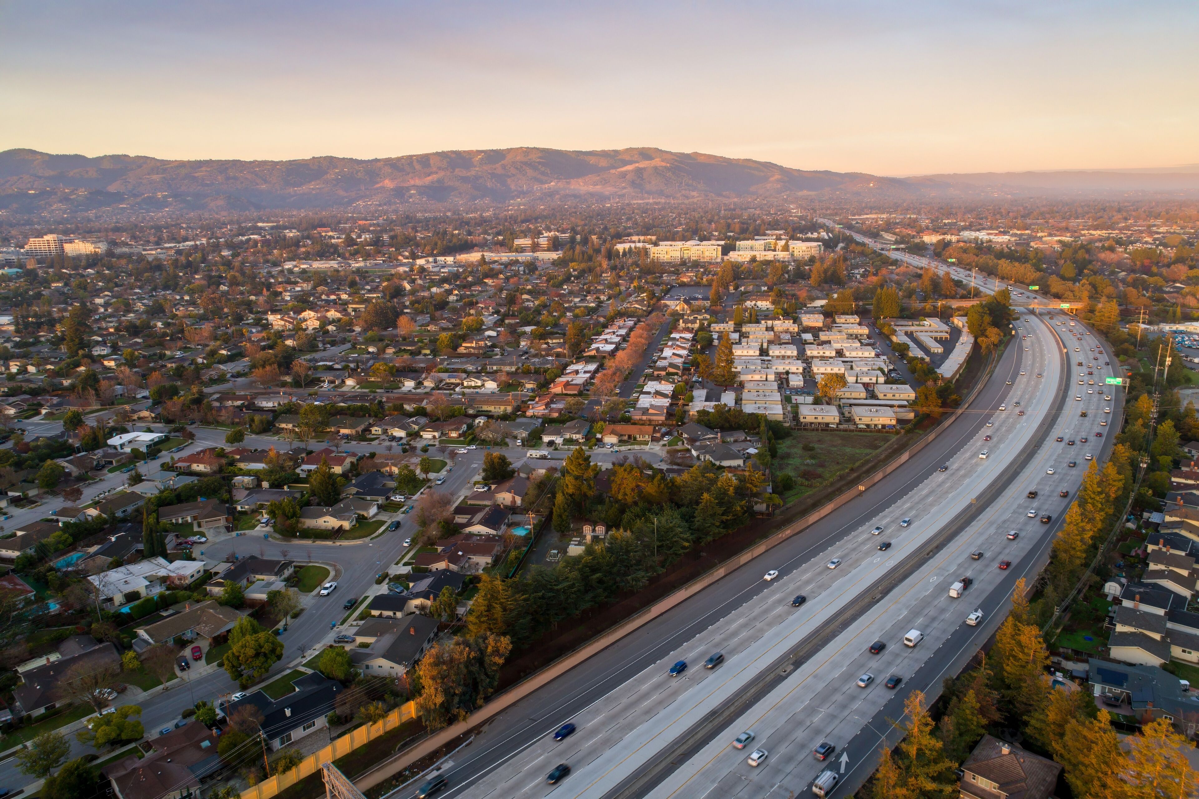 Aerial view of cars commuting on Interstate 280. Residential areas and mountains in Sunnyvale, California, USA, showcasing urban transportation and suburban living.
