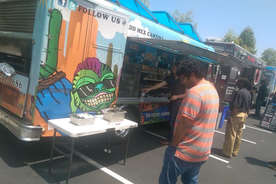 A food truck with colorful artwork and a man serving food.