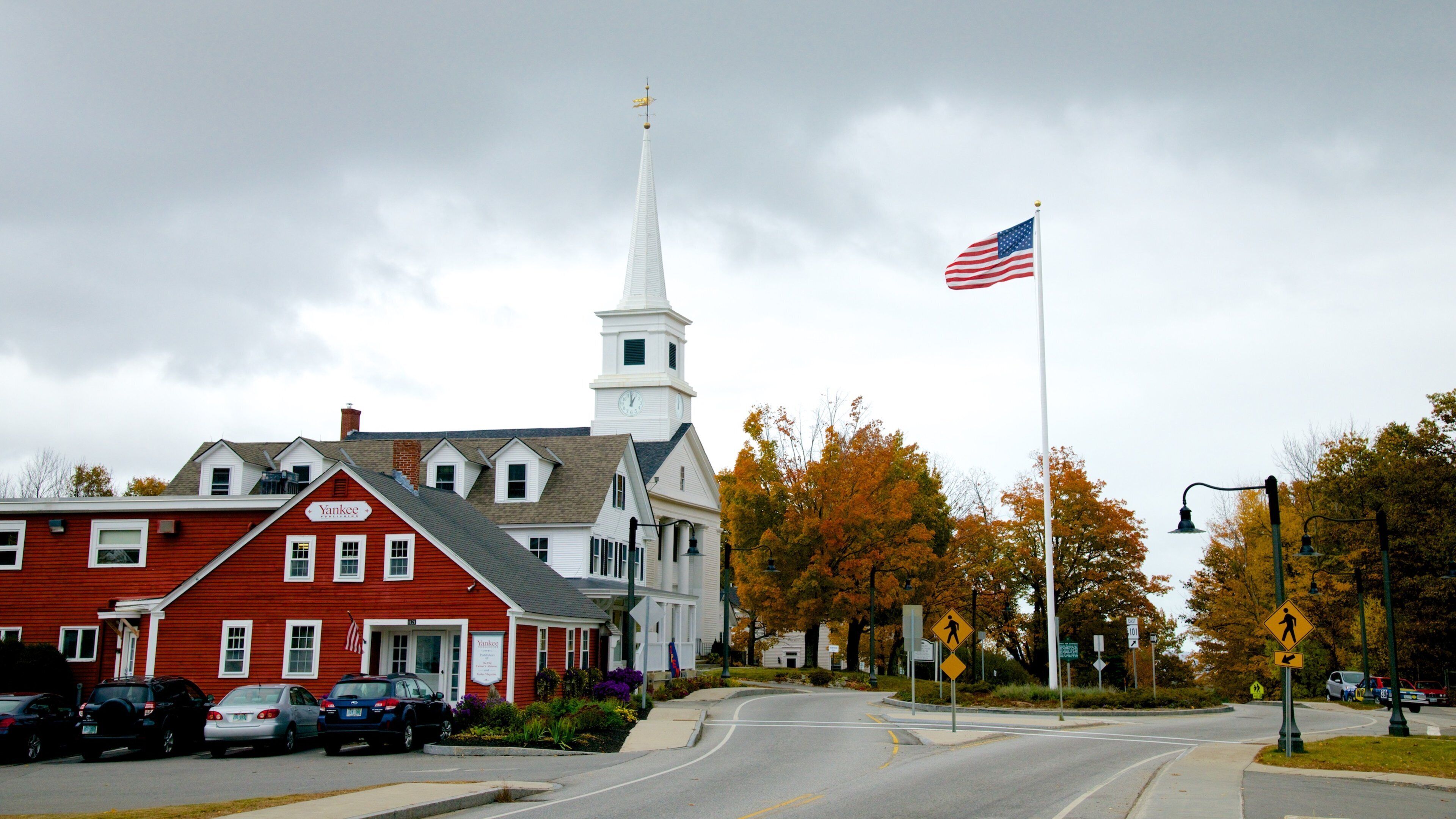 A church with a steeple, a red building with a sign, and an American flag.