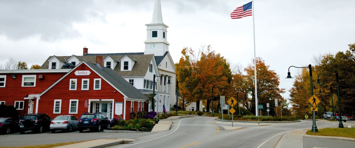 A church with a steeple, a red building with a sign, and an American flag.