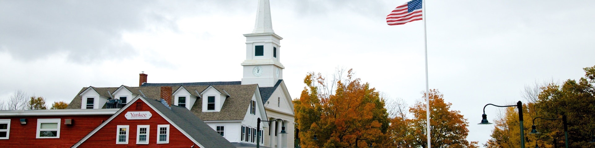 A church with a steeple, a red building with a sign, and an American flag.