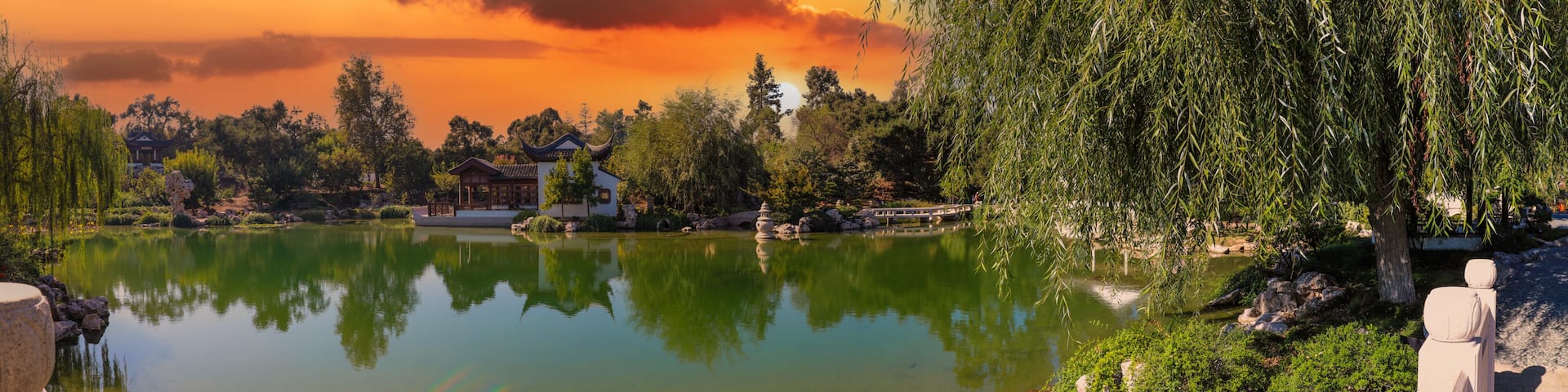 A serene lake with reflections, surrounded by trees and traditional buildings.