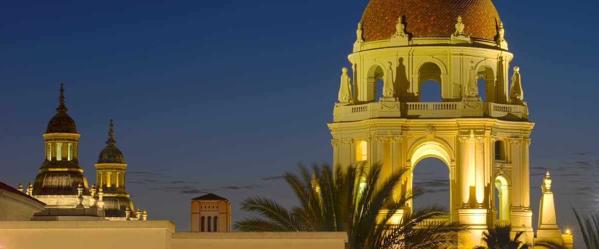 Una gran cúpula iluminada con estatuas, una luna creciente y dos cúpulas más pequeñas al fondo.